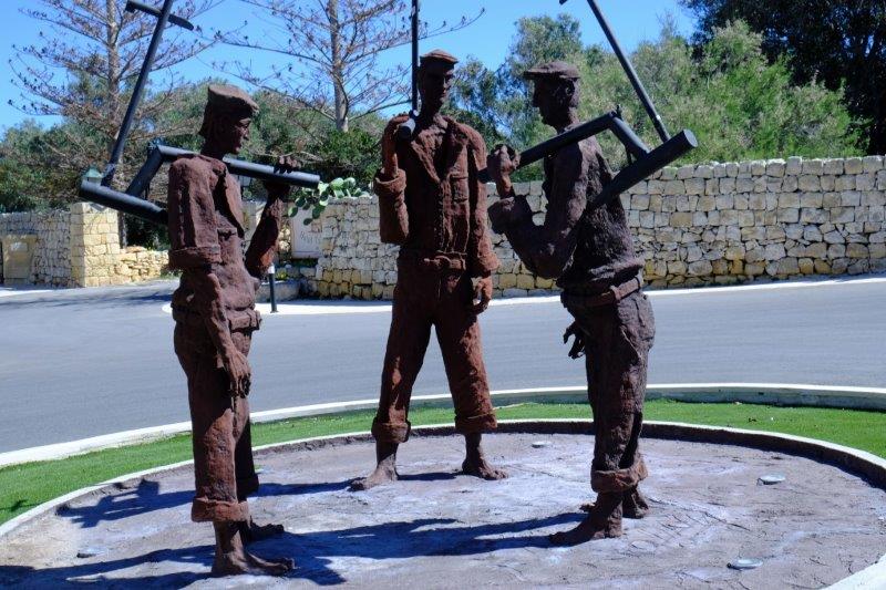 Statue of 3 generations of farm workers holding traditional ploughs at Ta Cenc
