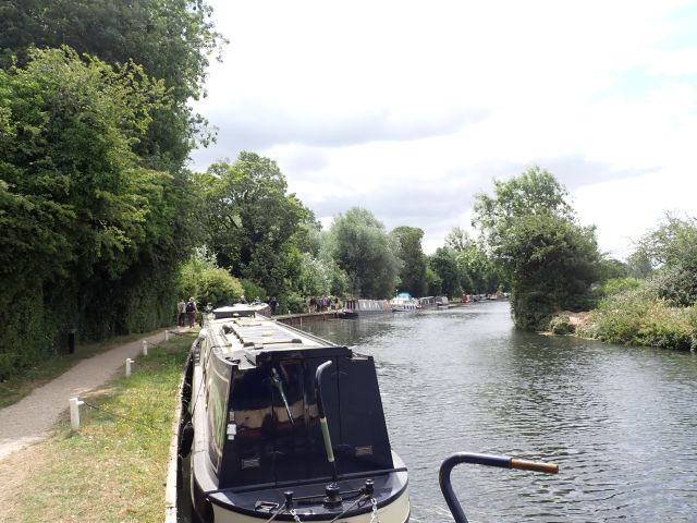 Narrowboat on scenic canal surrounded by trees.
