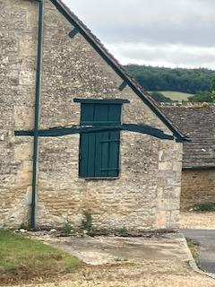 Old stone cottage with green window shutter.