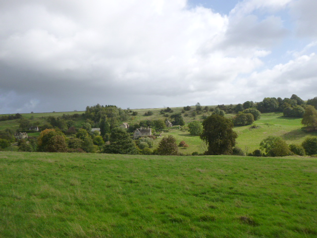 Countryside landscape with green hills and cloudy sky.