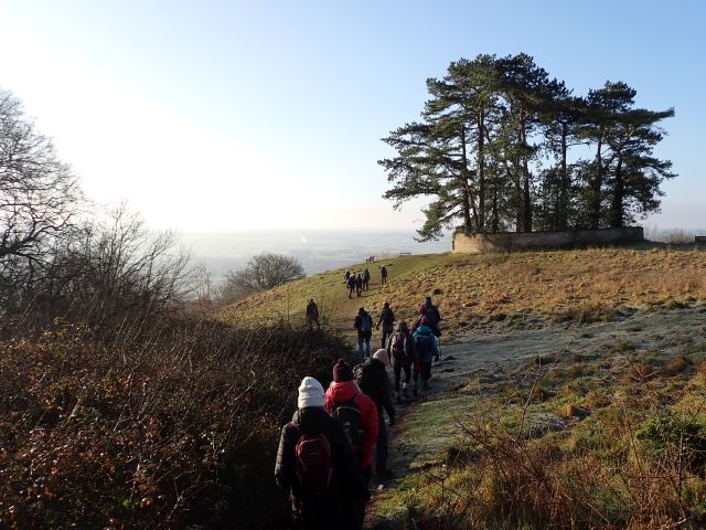 Group hiking on sunny, frosty hillside path.