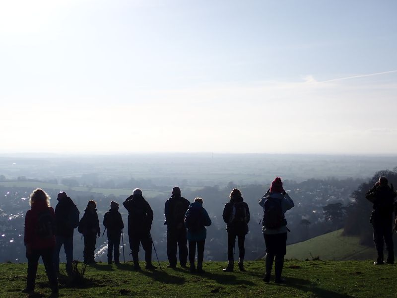 Group of walkers overlooking panoramic countryside view.