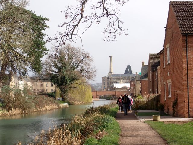 Riverside path with people walking and historic buildings