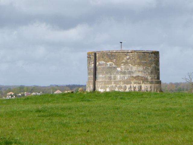 Concrete cylindrical structure in grassy field under cloudy sky