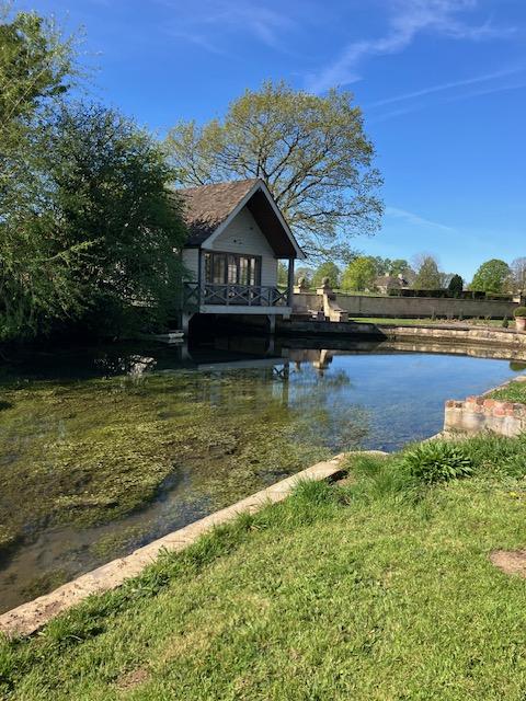 Lakeside boathouse beside clear pond under blue sky